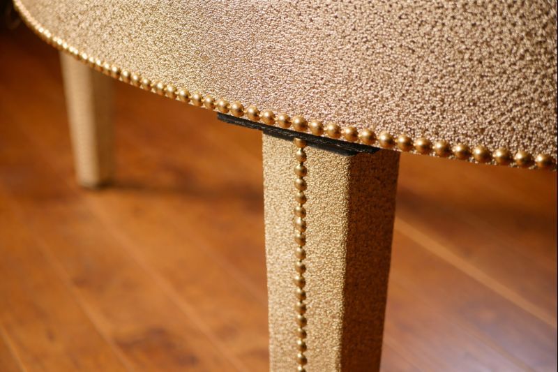 KeyGrand gold textured skai covering macro detail showing premium material quality and decorative gold nail trim on hardwood floor